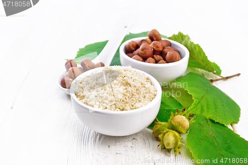 Image of Flour and hazelnuts in bowls on wooden board