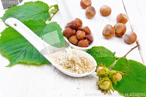 Image of Flour and hazelnuts in spoons on board