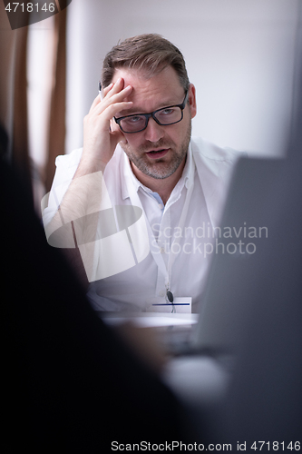 Image of Business man writing notes while working on laptop