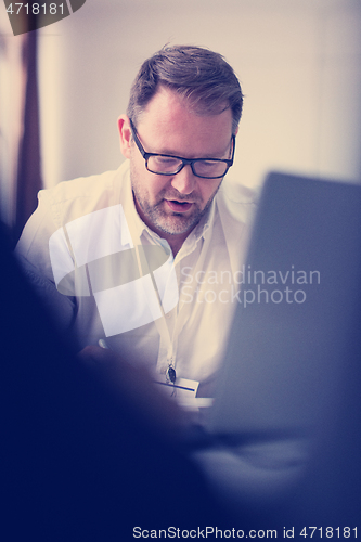 Image of Business man writing notes while working on laptop