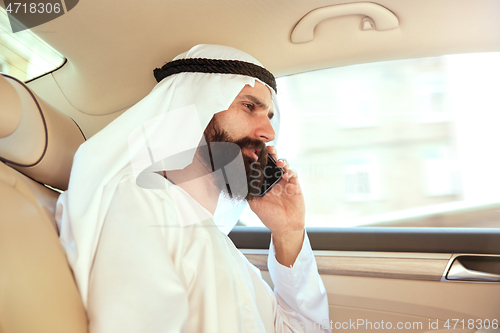 Image of Arabian saudi businessman working in his car
