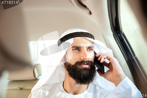 Image of Arabian saudi businessman working in his car