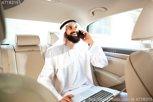 Image of Arabian saudi businessman working in his car