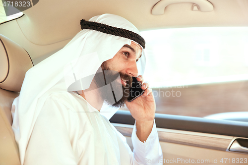 Image of Arabian saudi businessman working in his car
