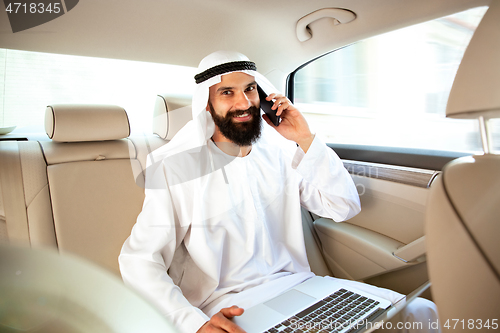 Image of Arabian saudi businessman working in his car