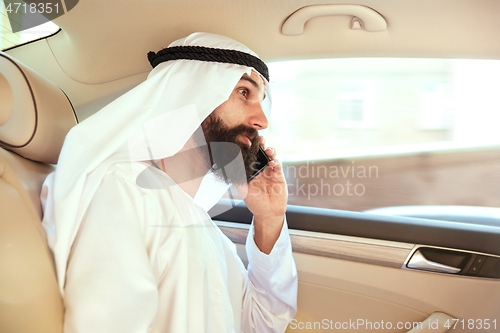 Image of Arabian saudi businessman working in his car