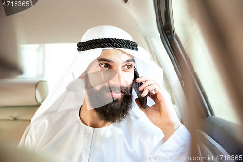 Image of Arabian saudi businessman working in his car