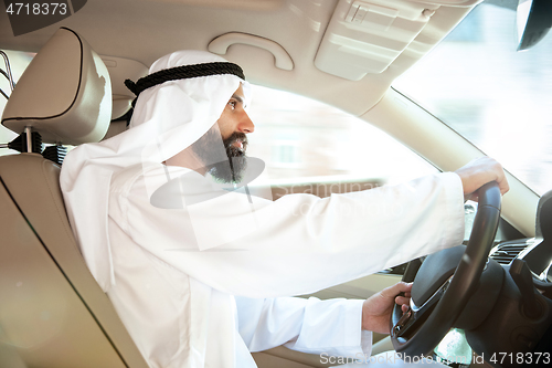 Image of Arabian saudi businessman driving hir car