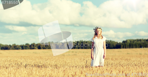 Image of happy young woman in flower wreath on cereal field