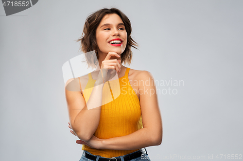 Image of happy thinking young woman in mustard yellow top