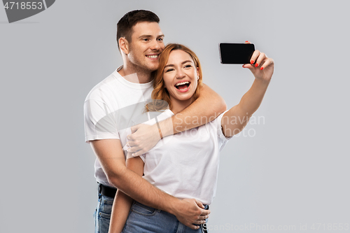 Image of happy couple in white t-shirts taking selfie