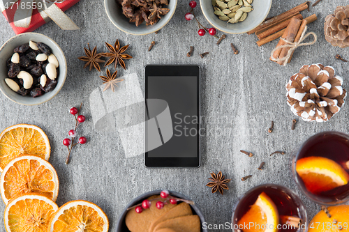 Image of smartphone, hot mulled wine and christmas spices