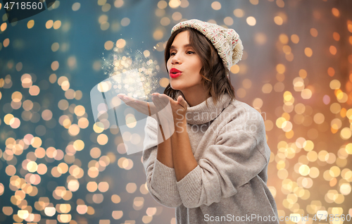 Image of young woman in knitted winter hat sending air kiss