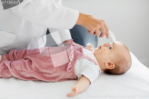 Image of doctor with thermometer measures baby temperature