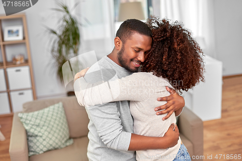 Image of happy african american couple hugging at home