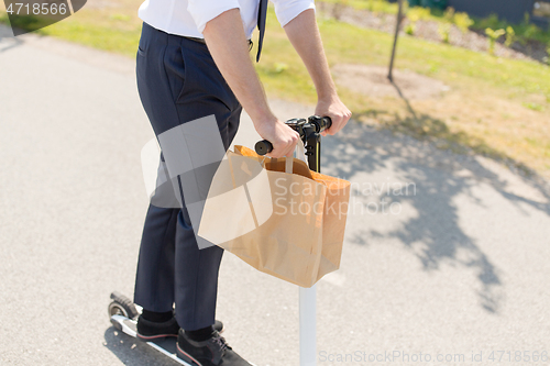 Image of businessman with takeaway paper bag riding scooter