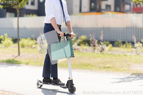 Image of businessman with shopping bag riding scooter