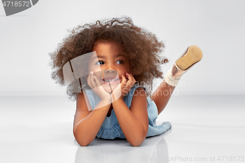 Image of happy little african american girl lying on floor