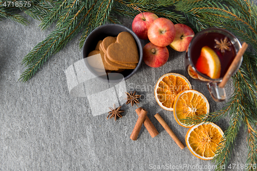 Image of glass of hot mulled wine, cookies, apples and fir