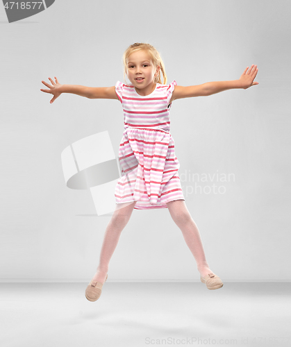 Image of happy little girl in striped dress jumping