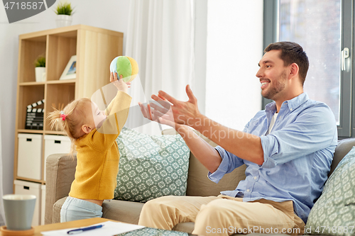 Image of father and baby daughter playing with ball at home