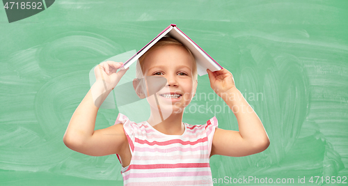 Image of little girl with book on top of her head at school