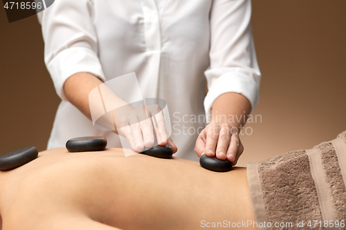 Image of close up of woman having hot stone massage at spa