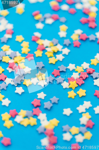 Image of star shaped pastry sprinkles on blue background