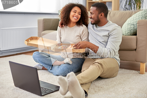 Image of happy african american couple eating pizza at home