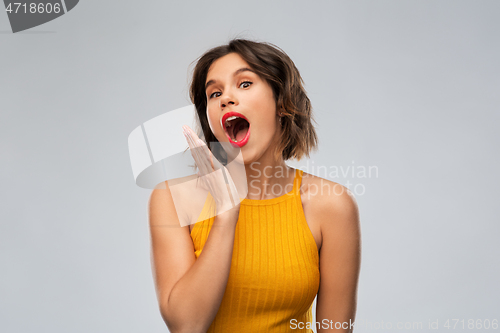 Image of surprised young woman in mustard yellow top