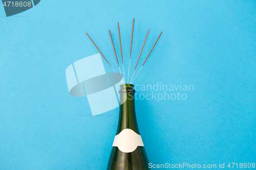 Image of champagne bottle with sparklers on blue