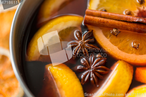 Image of pot with hot mulled wine, orange slices and spices