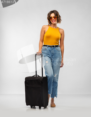 Image of happy young woman in sunglasses with travel bag