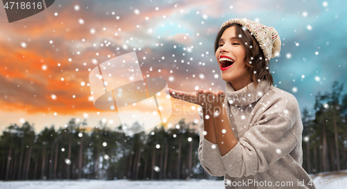 Image of woman in hat sending air kiss over winter forest