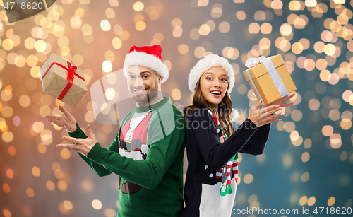 Image of happy couple in christmas sweaters with gifts