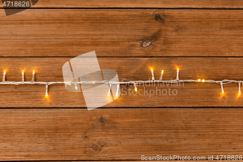 Image of christmas garland lights on wooden background