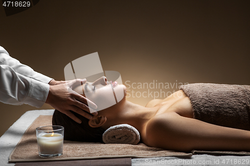 Image of woman having face and head massage at spa