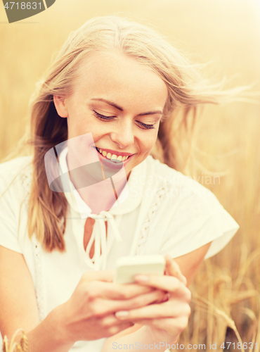 Image of happy young woman with smartphone on cereal field