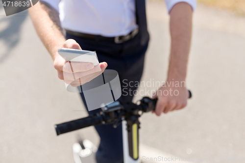 Image of businessman with smartphone and electric scooter