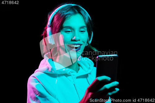 Image of woman in headphones with smartphone in neon lights