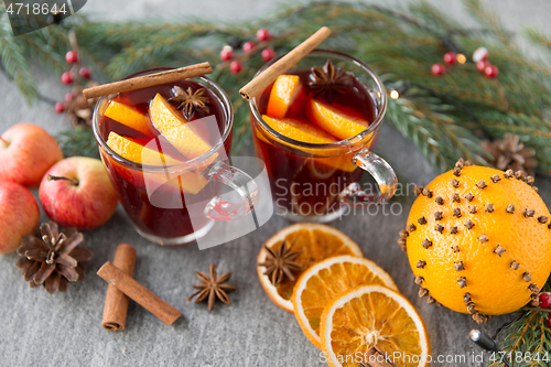 Image of glass of hot mulled wine, cookies, apples and fir