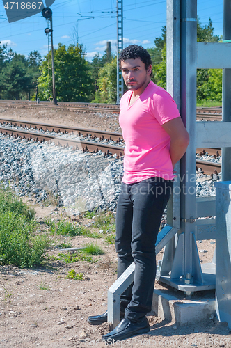 Image of Handsome young guy in pink t-shirt watching on you