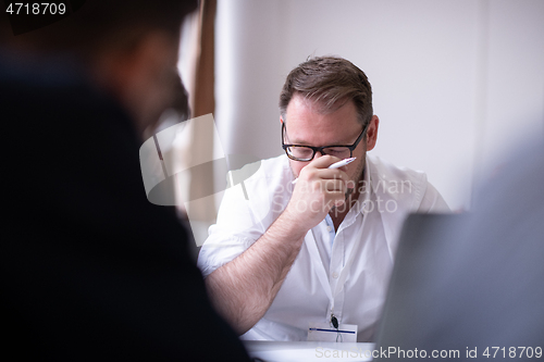 Image of Business man writing notes while working on laptop
