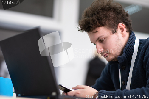 Image of Young casual businessman using smartphone