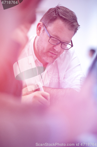 Image of Business man writing notes while working on laptop