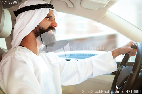 Image of Arabian saudi businessman driving hir car