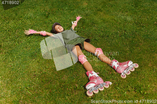 Image of Teenage girl in a helmet learns to ride on roller skates outdoors