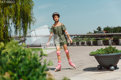 Image of Teenage girl in a helmet learns to ride on roller skates outdoors