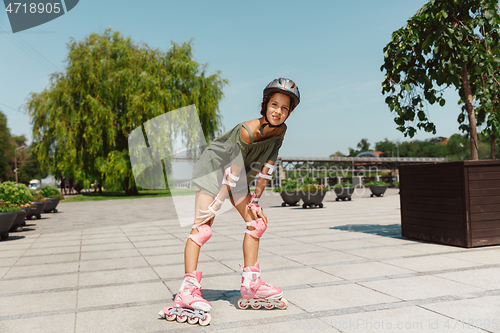 Image of Teenage girl in a helmet learns to ride on roller skates outdoors