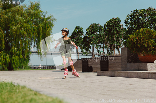 Image of Teenage girl in a helmet learns to ride on roller skates outdoors